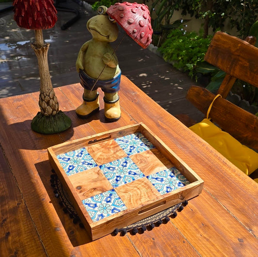 Decorative wooden tray with a checkered pattern on a wooden table outdoors.