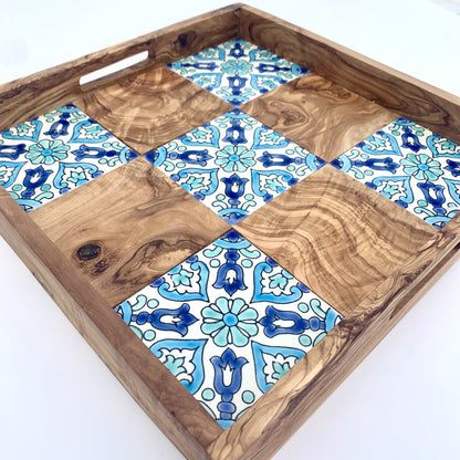 Wooden tray with blue and white patterned tiles on a white background