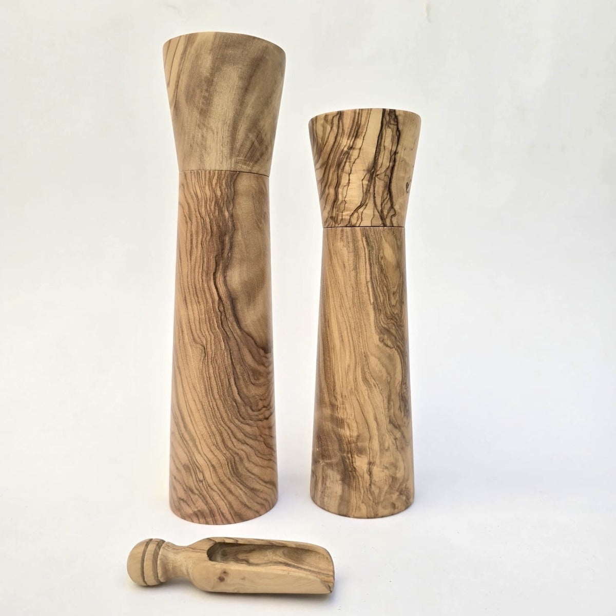 Two wooden salt or pepper grinders with a small scoop on a white background