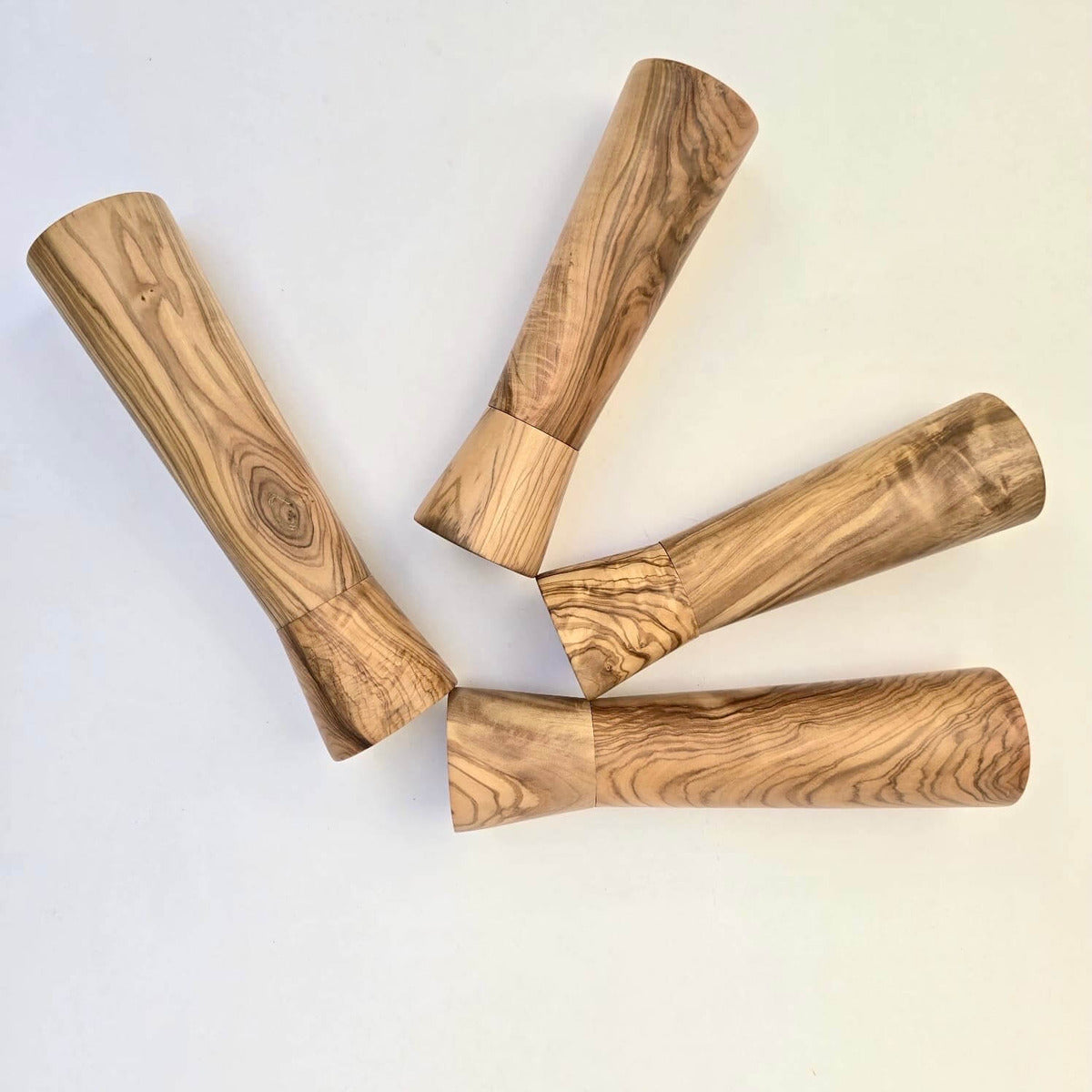 Four wooden pepper grinders on a light background