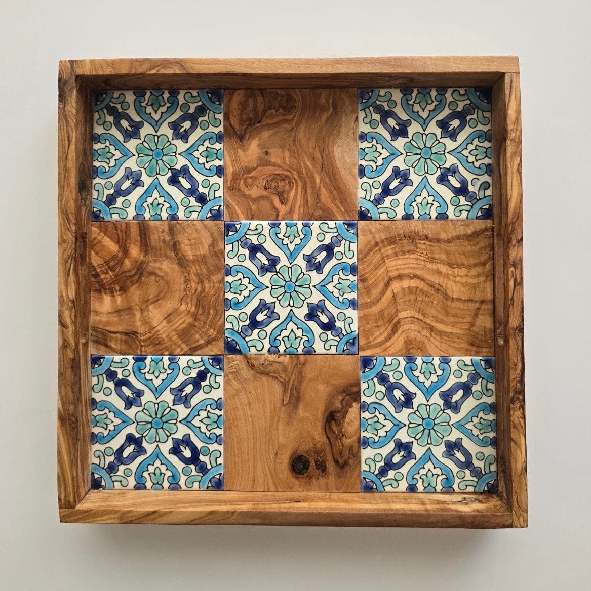 Wooden tray with a patterned tile design on a white background
