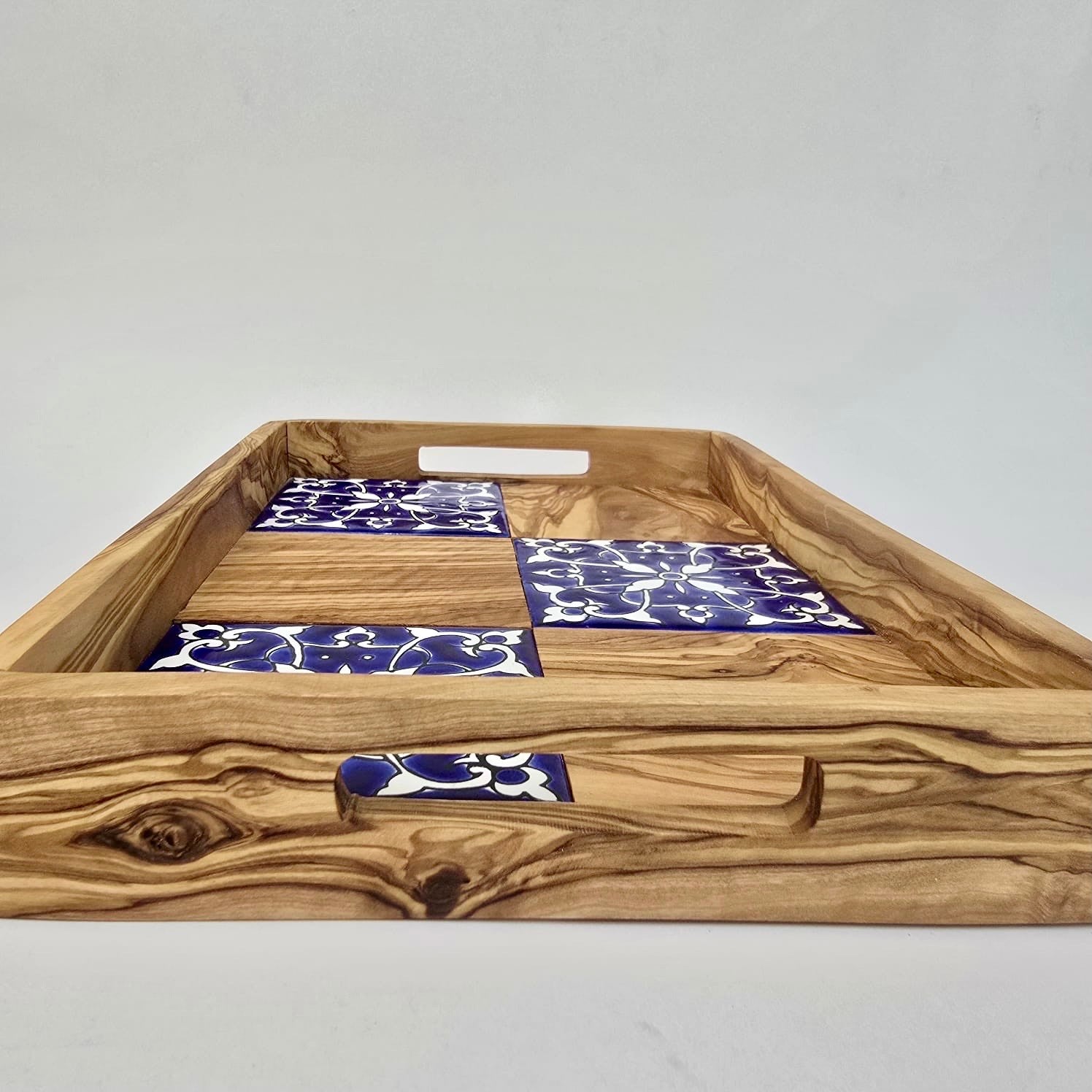 Wooden tray with blue and white patterned tiles on a plain background