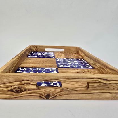 Wooden tray with blue and white patterned tiles on a plain background