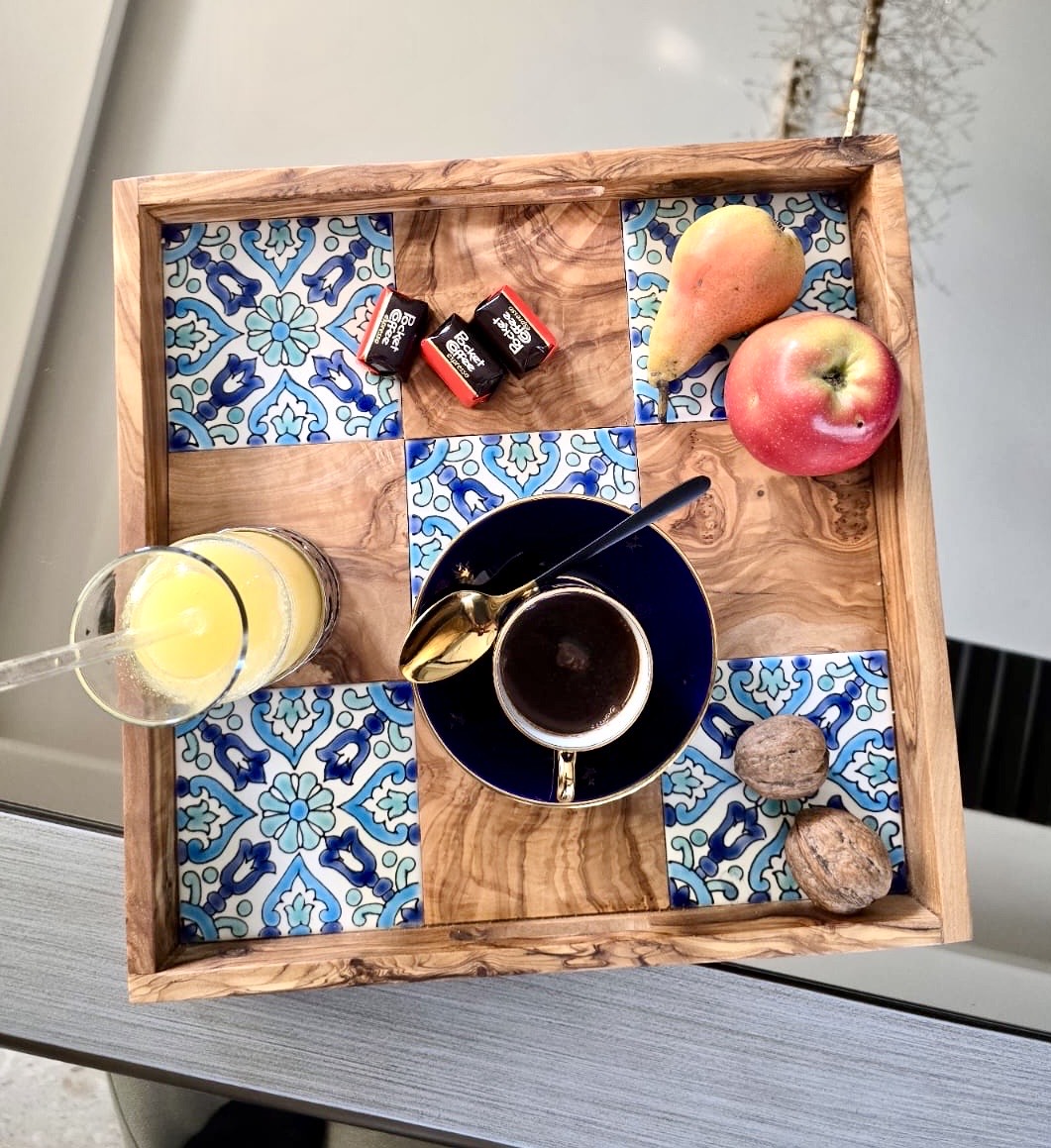 Wooden tray with a checkered pattern containing a cup, a juice glass, and fruits.