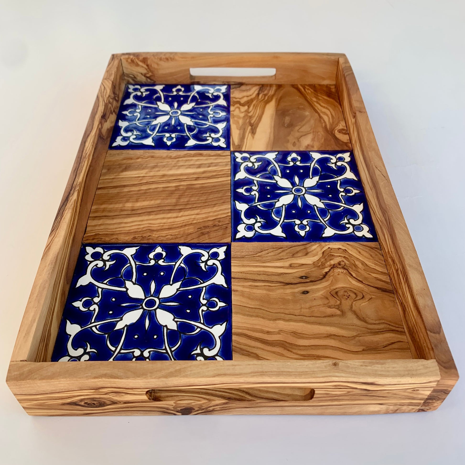 Wooden tray with blue and white patterned tiles on a white background